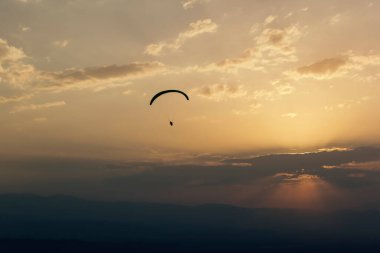 Paraglider bulutlarda uçar gün batımında, arka planda, bulanık