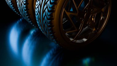 Altın alaşımlı jantları olan birkaç araba tekerleği, yumuşak mavi ışıkla aydınlatılmış yansıtıcı siyah bir yüzeye dizilmiş ve dramatik bir otomotiv stüdyosu görüntüsü yaratıyor.