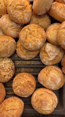 Pastane tepsisinde üst üste dizilmiş yuvarlak ekmek rulolarının videosunu kapat. Taze pişmiş çörekler, yemek pişirme ve ticari tasarım için fotokopi alanı olan basit bir gıda arkaplanı olarak gösterilir..