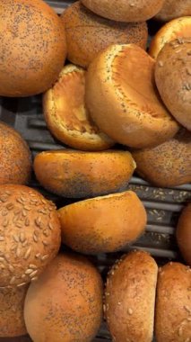 Fırın tepsisinde sergilenen altın çörekler ve tohum rulolarını gösteren video. Taze pişmiş yiyecekler, fotokopi alanı olan sıcak dokulu yiyecek arka planı oluşturur..