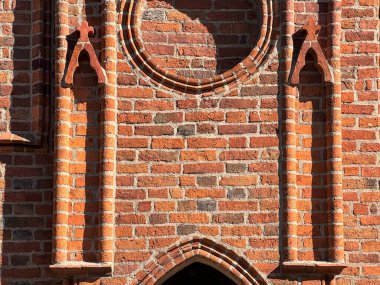 1370 yılında Avrupa 'da inşa edilen ve dairesel tuğla süslemeleri ve kemer girişini gösteren gotik kilise cephesinin ayrıntılı görüntüsü. Ortaçağ Katolik mimarisi örneği.