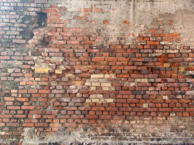Yaş ve yıpranmayı gösteren sert kırmızı tuğla bir duvara yakın durun. Yüzey, tasarım ve illüstrasyon için kullanışlı bir grunge dokusu sağlar..