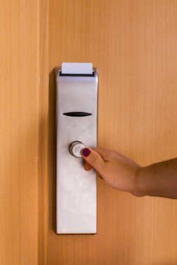 Kadın misafir, anahtar kartıyla elektronik kapı kilidini açıyor. Seyahatleri sırasında rahat bir konaklama için otel odasına giriyor.