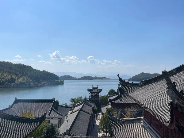 Geleneksel Çin mimarisinin manzarası Fuxian gölünün sakin sularına bakan katmanlı çatıları, yemyeşil ve Çin 'in yunnan bölgesinde uzak dağlarla çevrili.