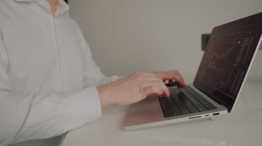 Ekranda hisse senedi ve kripto ticaret arayüzü bulunan dizüstü bilgisayarda finans, yatırım ve dijital ekonomiyi temsil eden profesyonel daktilo elleriName