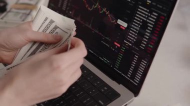 Bilgisayardaki borsa çöküşü grafiğinde para sayan eller, ekonomik kriz, ön x ticaret başarısızlığı ve belirsiz finansal geleceği temsil ediyor.