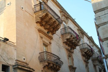 İtalya, Sicilya, Noto 'daki Nicolaci Sarayı' nın son barok tarzı balkonunda.