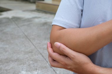 Tendon gerilmesinden ya da eklem iltihabından dirsek ağrısı olan bir sporcu. Hareket kabiliyeti, kas desteği ve fizyoterapi tedavisi için spor yaralanmaları bakımı.