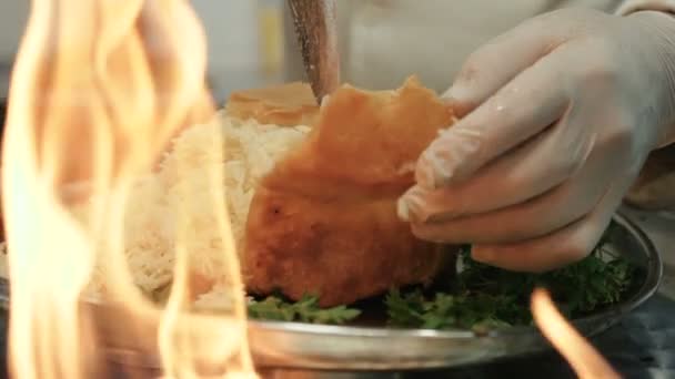 Rice pilaf is cooked on bread in the kitchen, on the background of fire — Stock Video