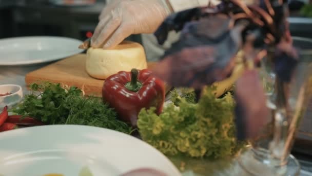 Schuss von einem Stück Käse in der Küche. Koch schneidet mit Messer ein Stück Käse drauf — Stockvideo