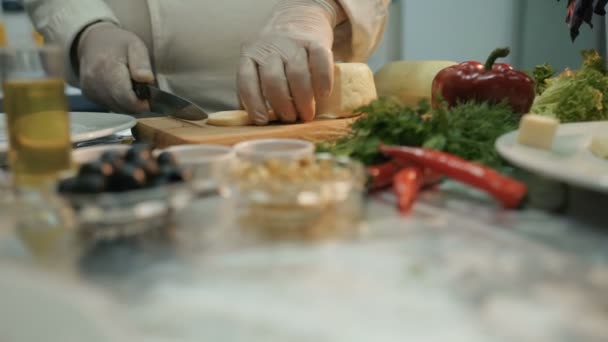 Schuss von einem Stück Käse in der Küche. Koch schneidet mit Messer ein Stück Käse drauf — Stockvideo