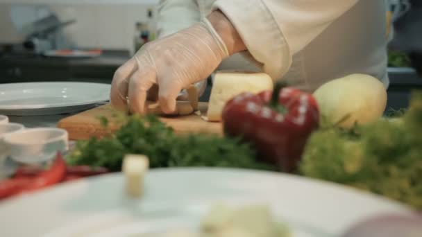 Tiro de um pedaço de queijo na cozinha. Chef está cortando um pedaço de queijo com uma faca — Vídeo de Stock