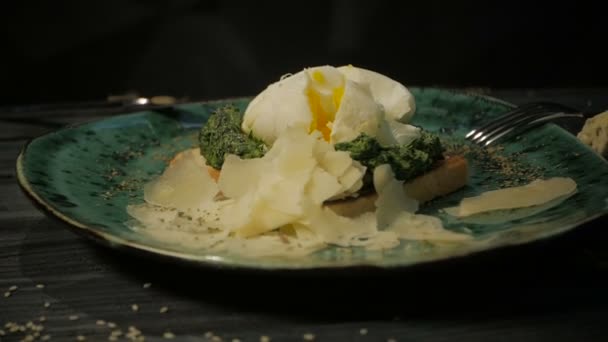 Pequeno-almoço. Ovo escalfado, salmão em alface em pão torrado. Em um fundo de madeira preto, dolly shot — Vídeo de Stock