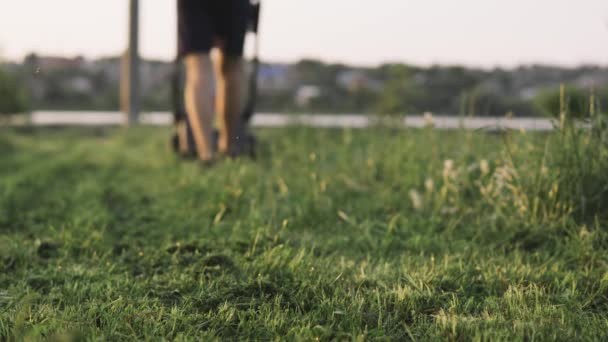 Green grass in the garden and man with lawn mower approaching in the background — Stock Video