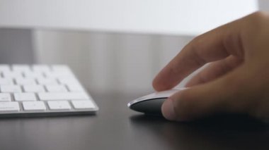 Ofiste bilgisayarın başında elinde fare tutan bir adamın resmi.