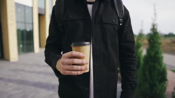 Knappe man wandelt in een moderne stedelijke omgeving en geniet van zijn smakelijke koffie — Stockvideo