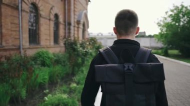 Sırt çantalı genç bir turist güneşli bir günde eski kasabada yürüyor.