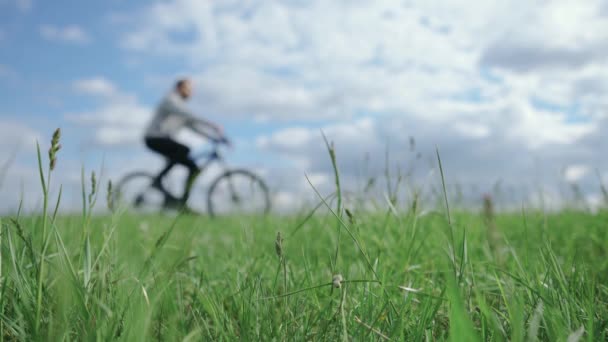 Cycliste fait du vélo sur l'herbe dans le champ par une journée ensoleillée, plan déconcentré