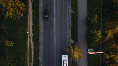 Gün batımında park alanındaki araba ve insanların hareketlerinin havadan görüntüsü.