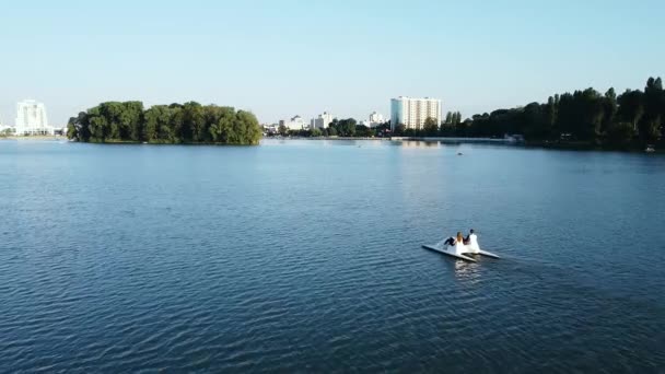 Vista aérea de los jóvenes amantes en pareja montan un catamarán en la zona del parque de la ciudad — Vídeos de Stock