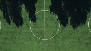 Koşu parkurları ve kortları olan doğal yeşil bir futbol sahasının üzerinden geçeceğiz.