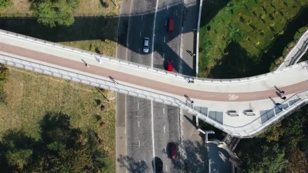 Widok z lotu ptaka na ludzi spacerujących po moście ze ścieżką rowerową wzdłuż drogi — Wideo stockowe