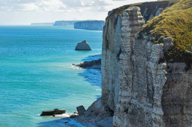 Normandiya 'daki Etretat kayalıklarından büyüleyici bir yaz manzarası, Kanal' ın turkuaz suları, katmanlı dalgalar, ve yeşil taçlandırılmış görkemli fildişi benzeri uçurumlar - unutulmaz bir doğa harikası.