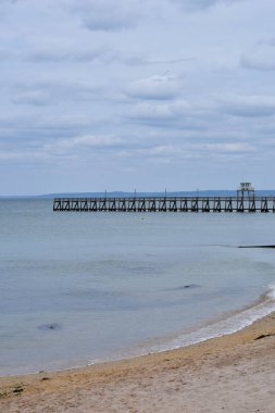 Normandiya 'daki Luc-sur-Mer plajının dikey bir görüntüsü. Uzun bir köprüsü var, manzara için mükemmel. Seyahat görselleri, doğa sahneleri ya da sakin bir yaşam tarzı içeriği için idealdir..
