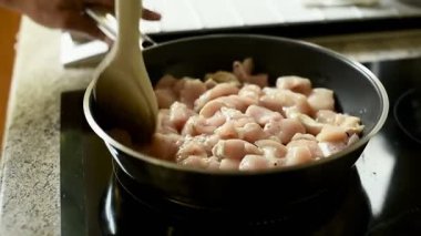 Dikey 4K videosu. Bir erkeğin eli kızartma tavasında kızartılmış eti ahşap bir spatulayla karıştırır. Modern yemek ve sağlıklı yemek teması.