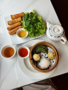 Sıcak, taze buğulanmış, bambu buharlı Çin yemeği, çıtır börek, taze marul ve mermer bir masada çay..