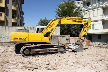 03 September 2025, Ankara, Turkey  Yellow crawler excavator on rubble at an urban demolition site beside residential buildings; editorial use for news, construction, infrastructure, redevelopment