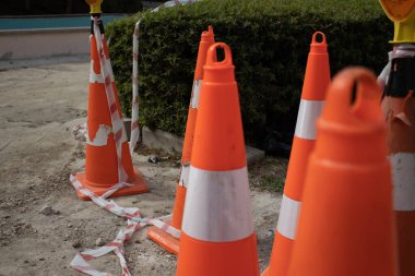 Closeup of used safety cones with reflective stripes, tape and warning lights on a construction site. Perfect for caution, traffic control, road maintenance and safety themes.