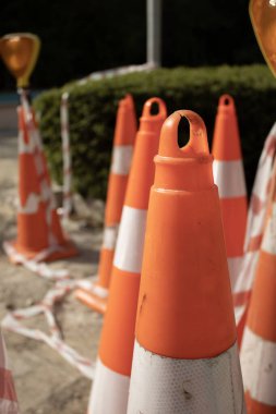 Closeup of used safety cones with reflective stripes, tape and warning lights on a construction site. Perfect for caution, traffic control, road maintenance and safety themes.