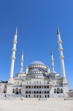 Frontal view of Kocatepe Mosque with central dome, tall minarets, marble facade and steps; religion, architecture, travel 