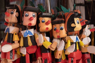 Handmade wooden marionette puppets in bright red and yellow colors, closeup view of detailed painted faces, ideal for nostalgic themes, print, mockup, retail or social media visuals.