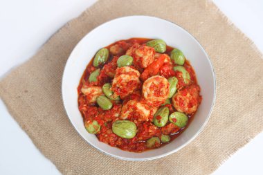 Acı fasulyeli Balado biberli karides (Udang Pete Balado) beyaz bir tabakta sunulmuştur, ılık için yumuşak kahverengi bir bez ile tasarlanmıştır, beyaz arka planda doğal pencere ışığı altında çekilir..