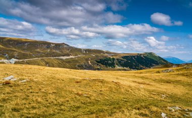 Romanya 'nın Parang Dağları' ndaki Galcescu Gölü yakınlarındaki vahşi Karpatlar 'da, canlı sonbahar renklerinin engebeli doruklarla buluştuğu nefes kesici bir sonbahar günü yaşayan bir gezgin görülüyor.