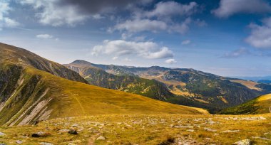 Romanya 'nın Parang Dağları' ndaki Galcescu Gölü yakınlarındaki vahşi Karpatlar 'da, canlı sonbahar renklerinin engebeli doruklarla buluştuğu nefes kesici bir sonbahar günü yaşayan bir gezgin görülüyor.