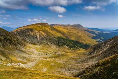 Romanya 'nın Parang Dağları' ndaki Galcescu Gölü yakınlarındaki vahşi Karpatlar 'da, canlı sonbahar renklerinin engebeli doruklarla buluştuğu nefes kesici bir sonbahar günü yaşayan bir gezgin görülüyor.