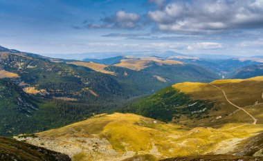 Romanya 'nın Parang Dağları' ndaki Galcescu Gölü yakınlarındaki vahşi Karpatlar 'da, canlı sonbahar renklerinin engebeli doruklarla buluştuğu nefes kesici bir sonbahar günü yaşayan bir gezgin görülüyor.