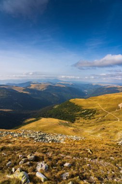 Romanya 'nın Parang Dağları' ndaki Galcescu Gölü yakınlarındaki vahşi Karpatlar 'da, canlı sonbahar renklerinin engebeli doruklarla buluştuğu nefes kesici bir sonbahar günü yaşayan bir gezgin görülüyor.