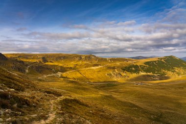 Romanya 'nın Parang Dağları' ndaki Galcescu Gölü yakınlarındaki vahşi Karpatlar 'da, canlı sonbahar renklerinin engebeli doruklarla buluştuğu nefes kesici bir sonbahar günü yaşayan bir gezgin görülüyor.