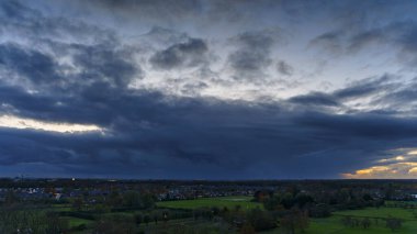 Hollanda 'nın kırsal kesimindeki yemyeşil tarlalara bakan nefes kesici balkon manzarası Amsterdam, Hollanda yakınlarındaki fırtınalı yaz günbatımında