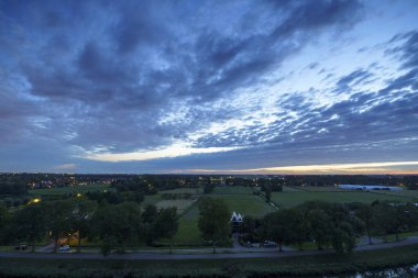 Hollanda 'nın kırsal kesimindeki yemyeşil tarlalara bakan nefes kesici balkon manzarası Amsterdam, Hollanda yakınlarındaki fırtınalı yaz günbatımında