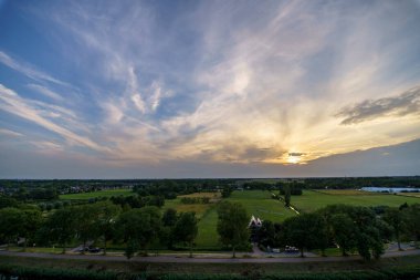 Hollanda 'nın kırsal kesimindeki yemyeşil tarlalara bakan nefes kesici balkon manzarası Amsterdam, Hollanda yakınlarındaki fırtınalı yaz günbatımında