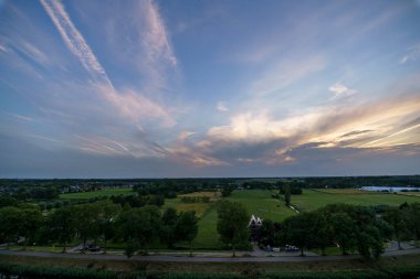 Hollanda 'nın kırsal kesimindeki yemyeşil tarlalara bakan nefes kesici balkon manzarası Amsterdam, Hollanda yakınlarındaki fırtınalı yaz günbatımında