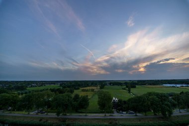 Hollanda 'nın kırsal kesimindeki yemyeşil tarlalara bakan nefes kesici balkon manzarası Amsterdam, Hollanda yakınlarındaki fırtınalı yaz günbatımında