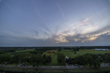 Hollanda 'nın kırsal kesimindeki yemyeşil tarlalara bakan nefes kesici balkon manzarası Amsterdam, Hollanda yakınlarındaki fırtınalı yaz günbatımında