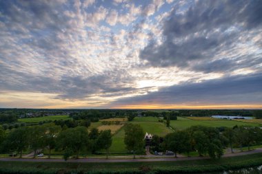 Hollanda 'nın kırsal kesimindeki yemyeşil tarlalara bakan nefes kesici balkon manzarası Amsterdam, Hollanda yakınlarındaki fırtınalı yaz günbatımında