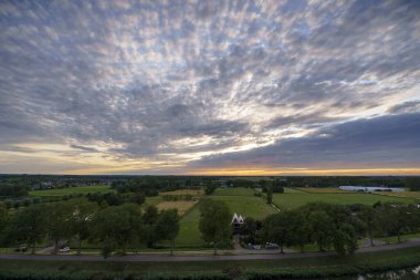 Hollanda 'nın kırsal kesimindeki yemyeşil tarlalara bakan nefes kesici balkon manzarası Amsterdam, Hollanda yakınlarındaki fırtınalı yaz günbatımında